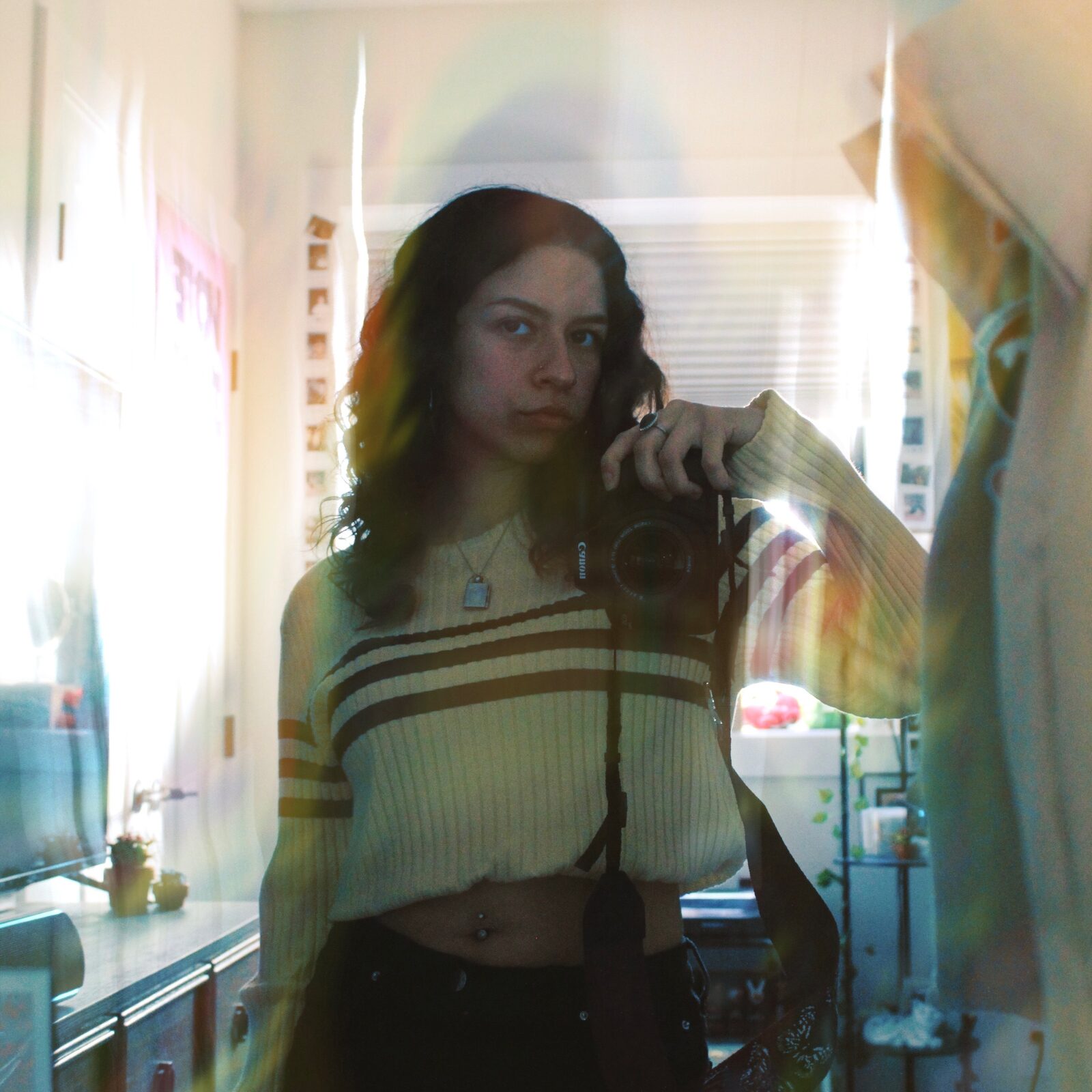 Jocelyn taking a mirror self-portrait with her camera in warm window light