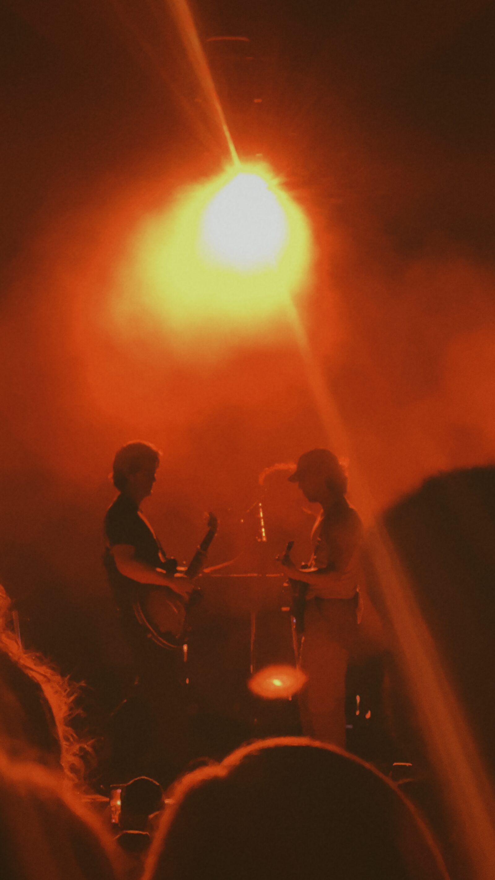 Performer silhouetted beneath red concert lights