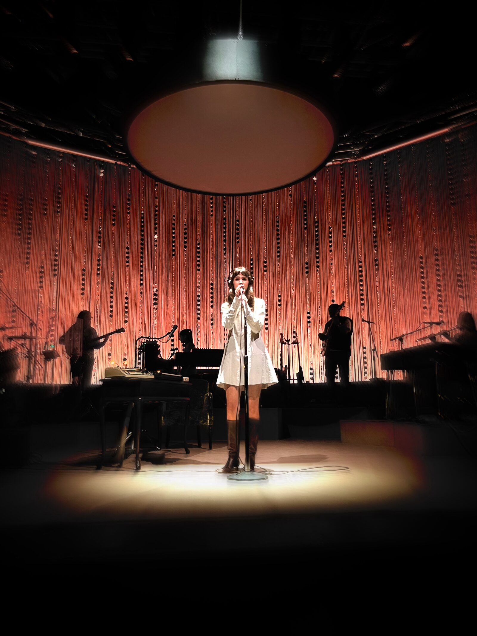 Solo performer standing inside a vivid green beam of stage light