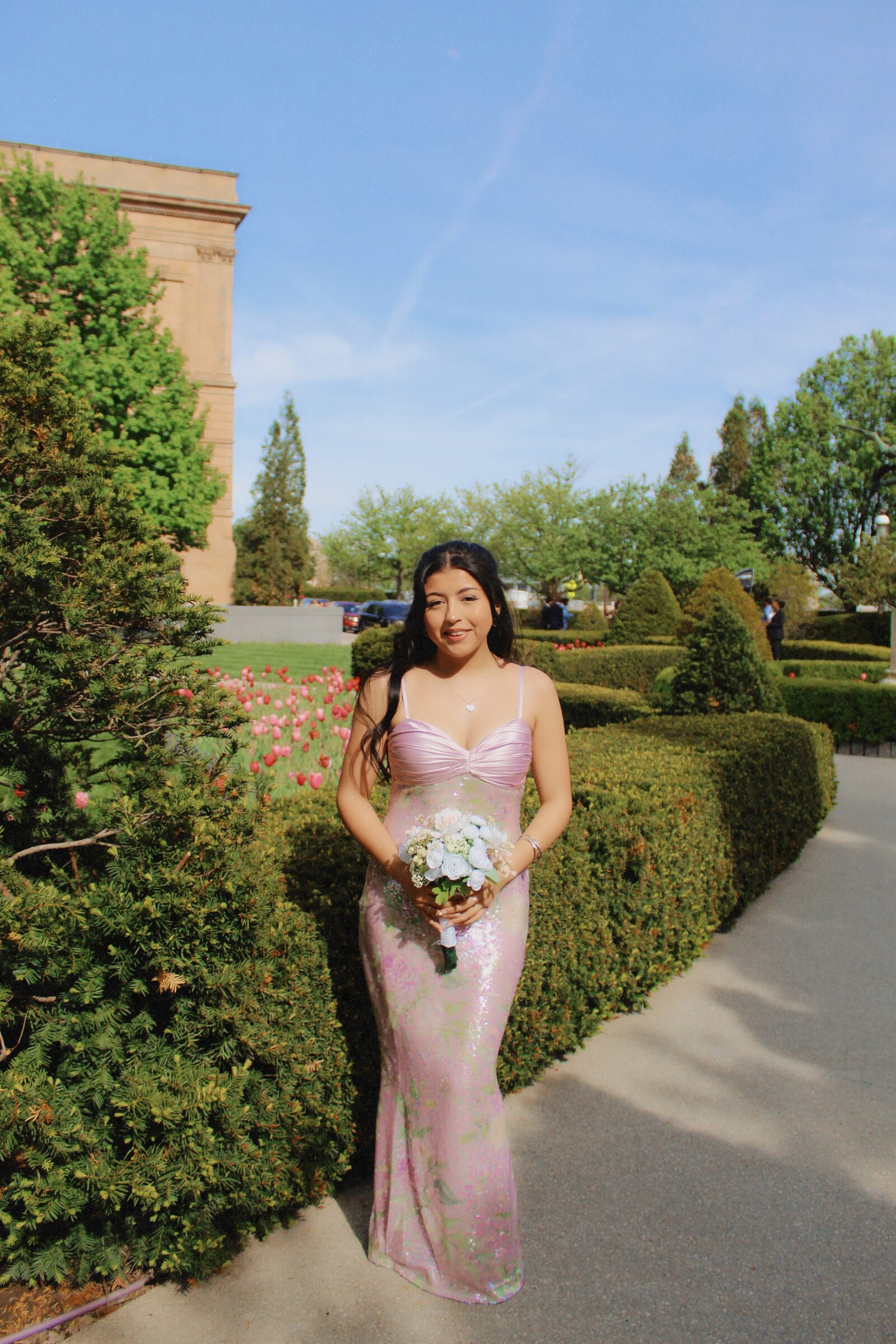 Woman in a pink dress walking through a formal garden