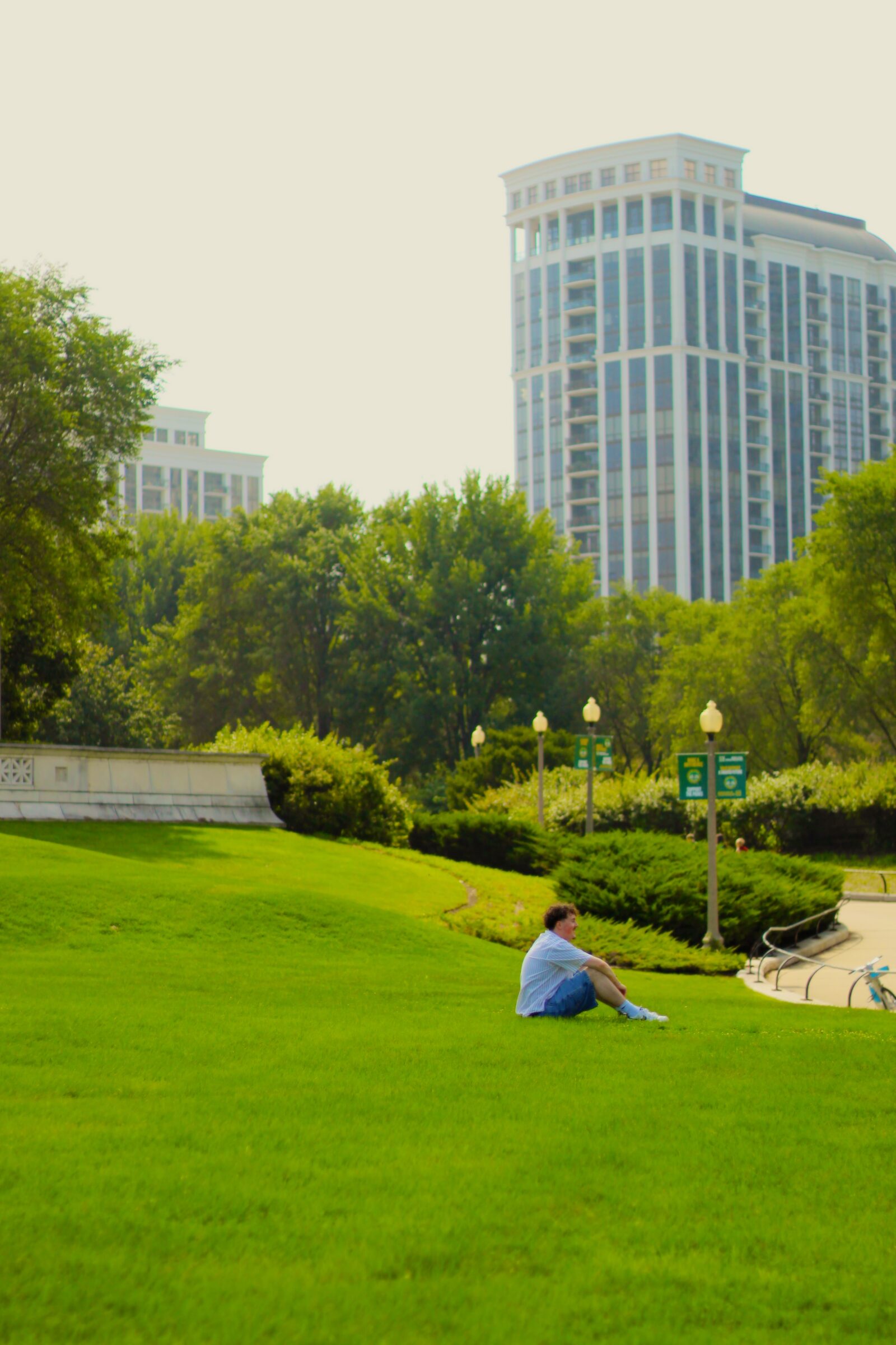 Woman holding flowers on a garden path with city buildings behind her
